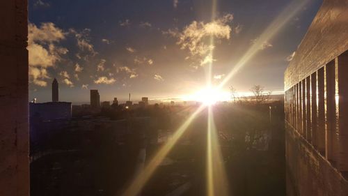 Sun shining through clouds over city