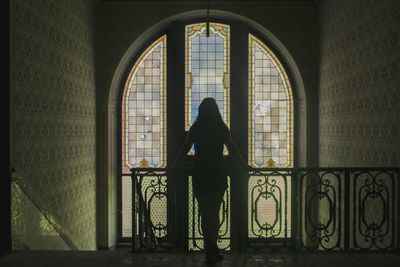 Rear view of woman standing by window in building