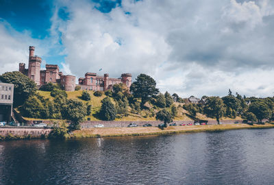 Scenic view of river by buildings against sky