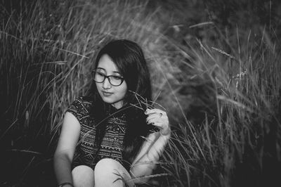 Young woman sitting amidst grass on field