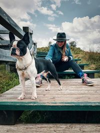 Full length of woman with dog sitting against sky