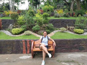 Portrait of woman sitting on bench against trees