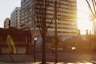 Road by buildings against sky during sunset