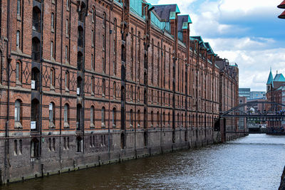 Bridge over river by buildings against sky