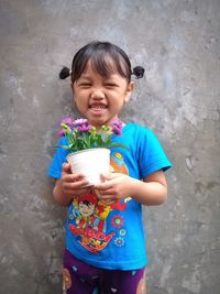 Portrait of cute girl holding while standing against wall