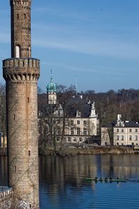 Buildings by river against sky in city