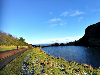 Scenic view of road by landscape against blue sky