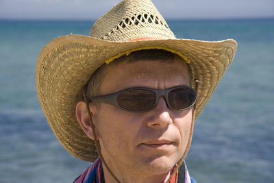 Close-up of man wearing sun hat against sea