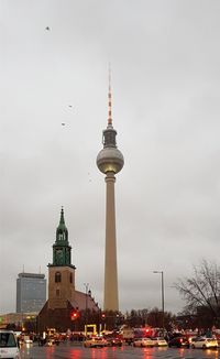 Communications tower and buildings in city against sky