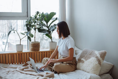 Young woman working on laptop at home in bed