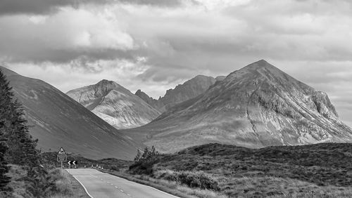 Road by mountains against sky