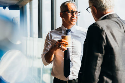 Young man holding camera while standing at home