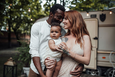 Cheerful family standing against van outdoors