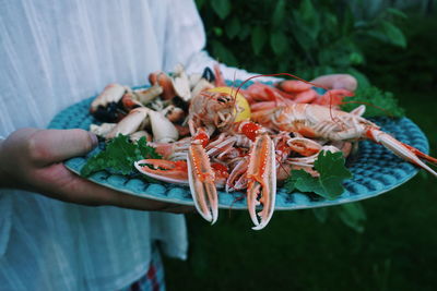 Midsection of woman holding seafood in plate