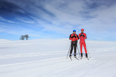 People skiing on snowy field against sky