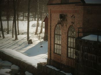 Snow covered house by trees during winter