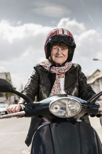 Active senior lady riding motor scooter in the city