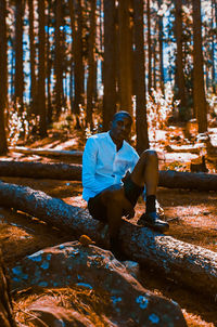 Man sitting on tree trunk in forest
