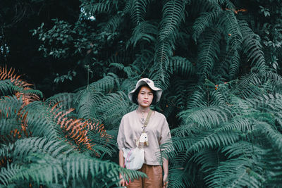 Portrait of young woman standing against plants