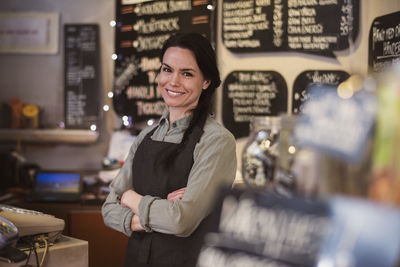 Portrait of smiling owner wearing apron standing at store