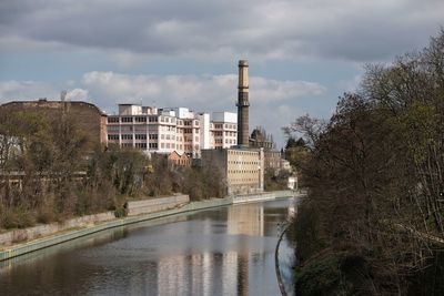 River by buildings against sky