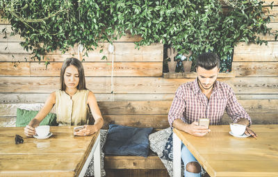 Couple using phones while having coffee in cafe