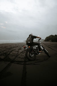 Man riding motorcycle on land against sky