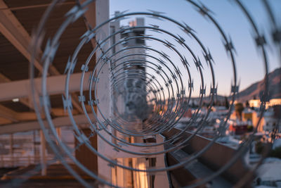 Close-up of metal fence against sky during sunset