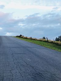 Road amidst field against sky