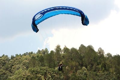 Low angle view of person paragliding against sky