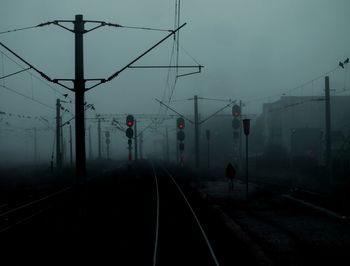 Diminishing perspective of railroad track against sky during foggy weather