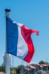 French flag on the mast over a blue sky.