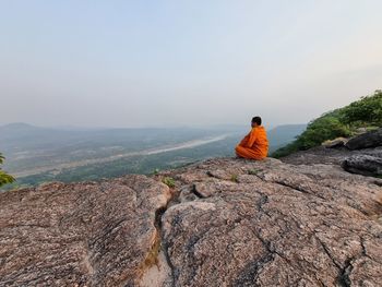 Rear view of man sitting on rock