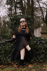 Portrait of young woman standing against plants