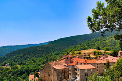 Houses on mountain against clear blue sky