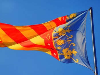 Low angle view of flag against blue sky