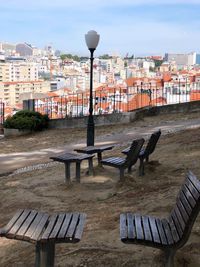 Empty bench on street against buildings in city