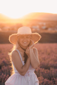 Beautiful smiling woman wear straw hat and dress stand in purple lavender flower field outdoor