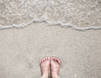 Low section of person legs on sand at beach