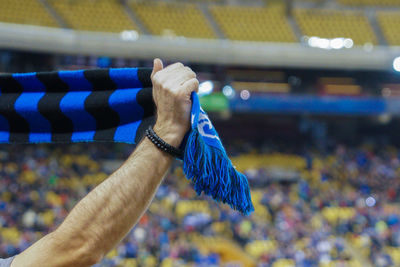 Cropped hand holding scarf at stadium