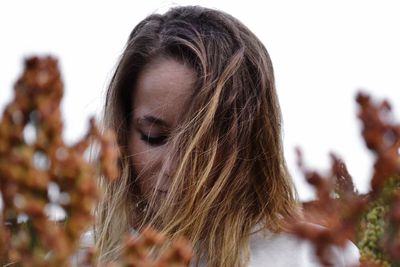 Close-up of woman with tousled hair against clear sky