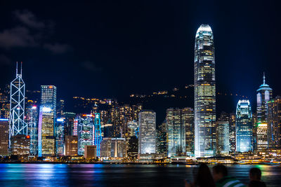 Illuminated buildings in city against sky at night