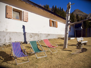 Empty chairs and tables in yard against building