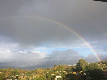 Rainbow over buildings in city against sky