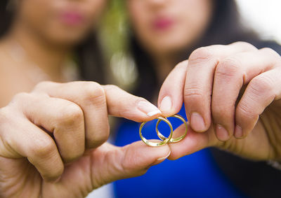 Close-up of lesbian couple holding wedding rings