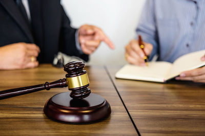 Midsection of lawyer sitting with man in courtroom