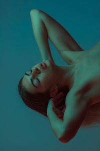 Close-up of woman lying down against blue background