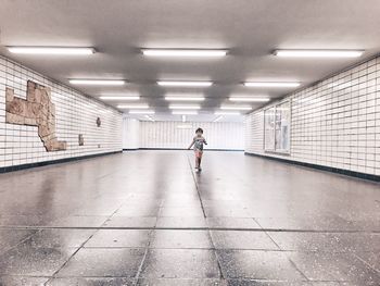 Full length of boy walking in illuminated subway