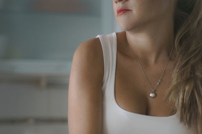 Midsection of woman in necklace at home