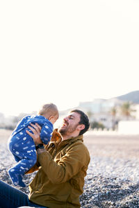 Father with daughter against sky